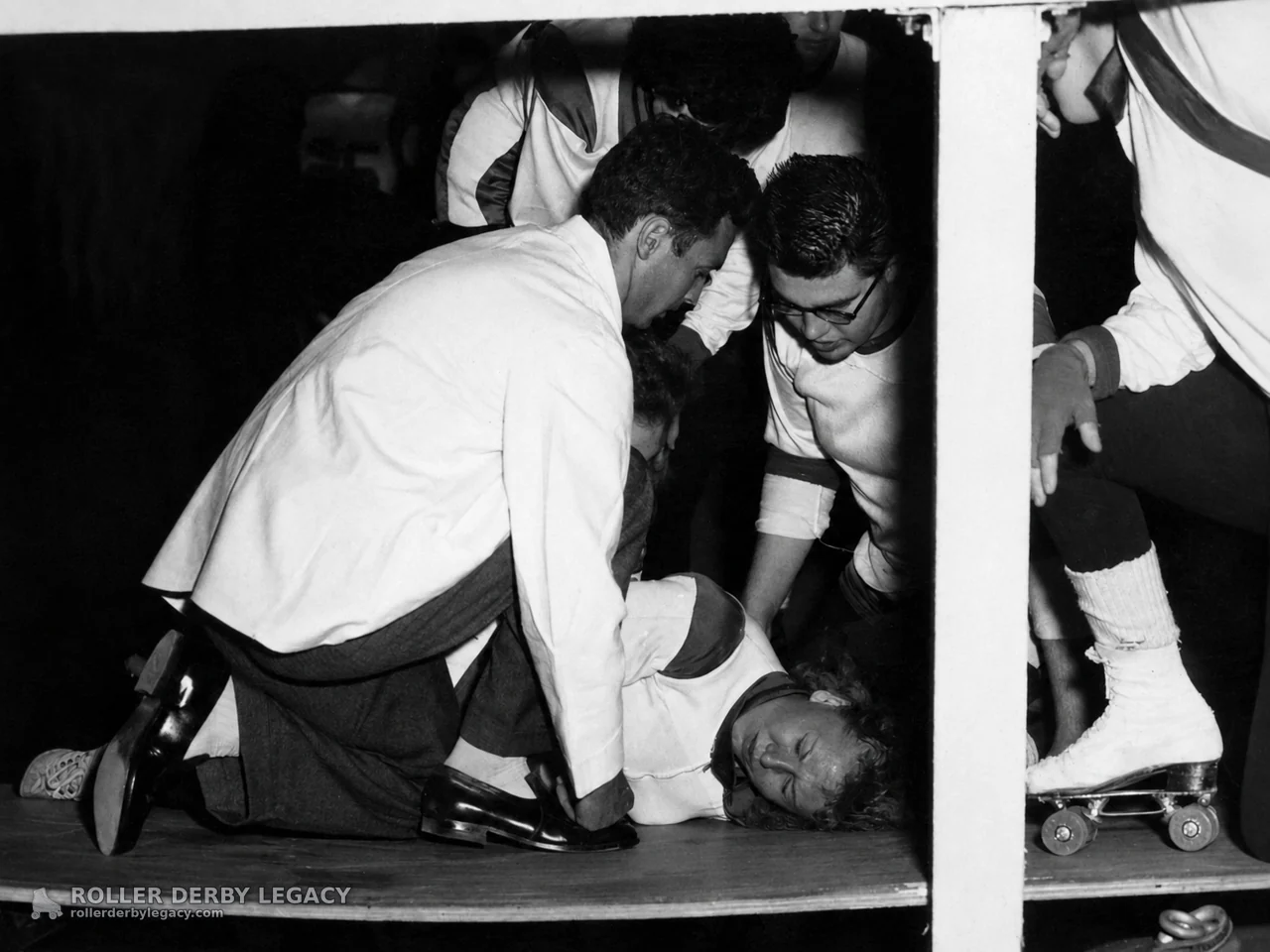Fallen Roller Skater Surrounded on Indoor Rink Floor