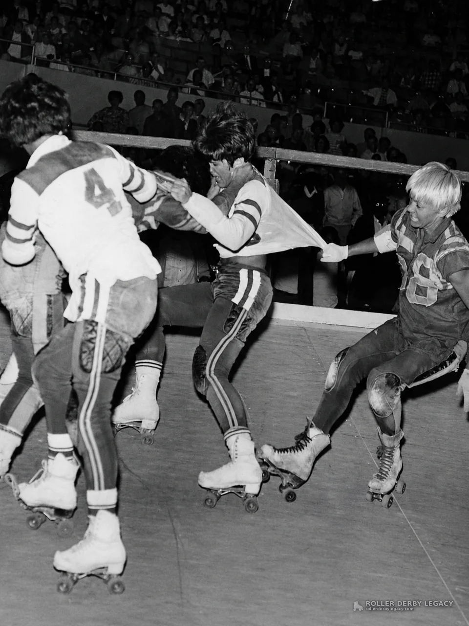 Roller derby skaters jostle before arena crowd