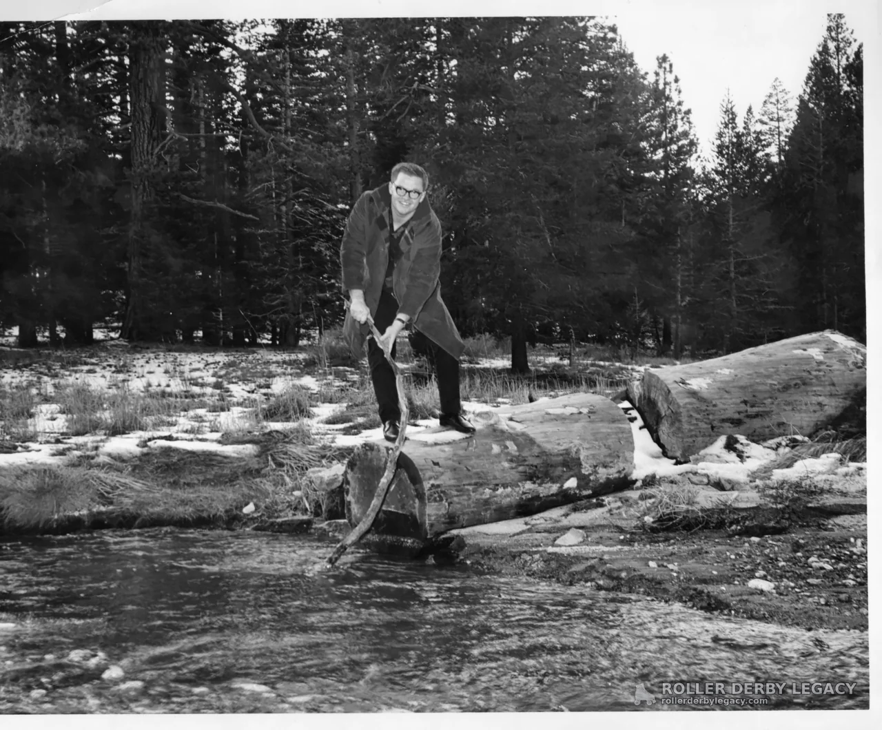 Man on Fallen Log Over a Snowy Creek