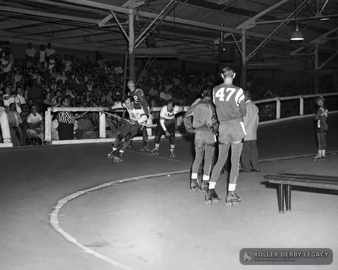 Roller Derby Skaters on an Indoor Track Before a Crowd