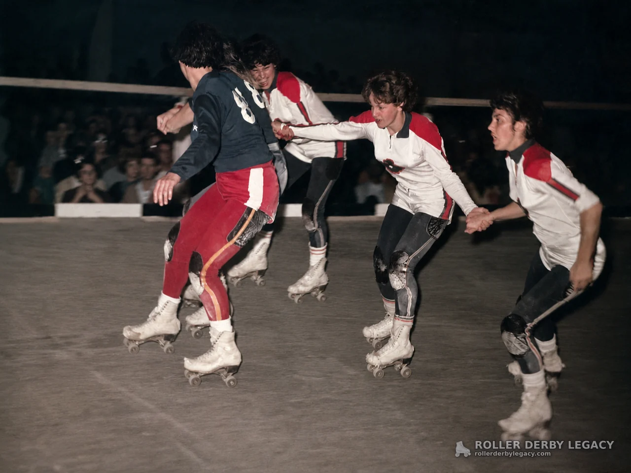 Four Roller Derby Skaters in Close Indoor Track Action