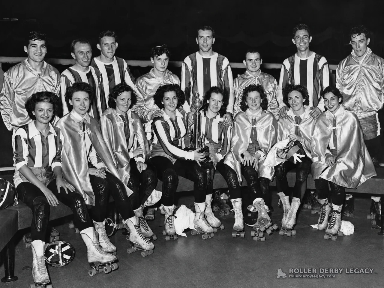 Roller skaters posing with trophy in rink