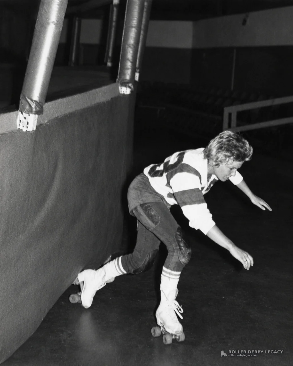Skater Leaning Low Beside Padded Rink Wall