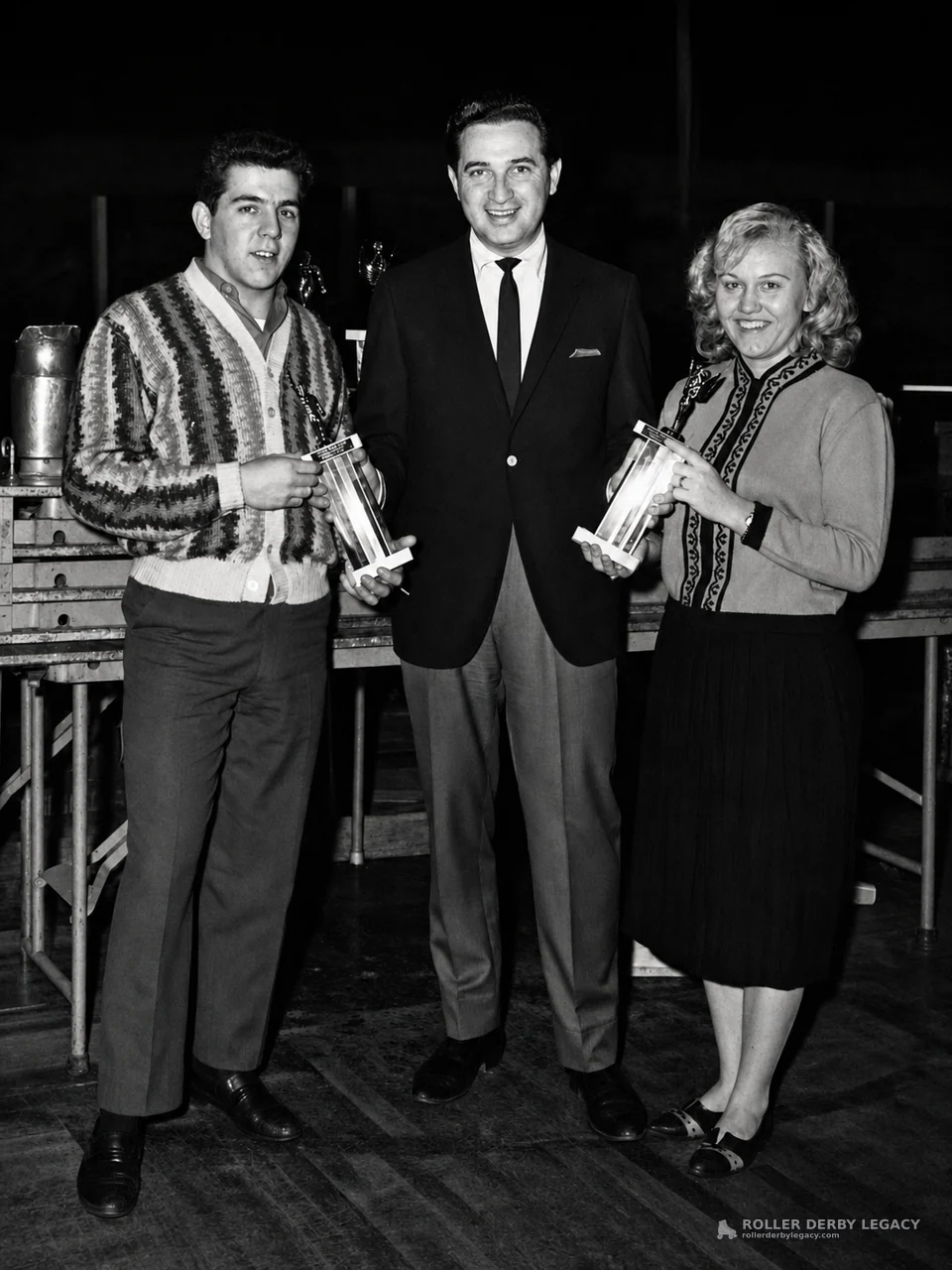 Three Adults Posing with Trophies Indoors