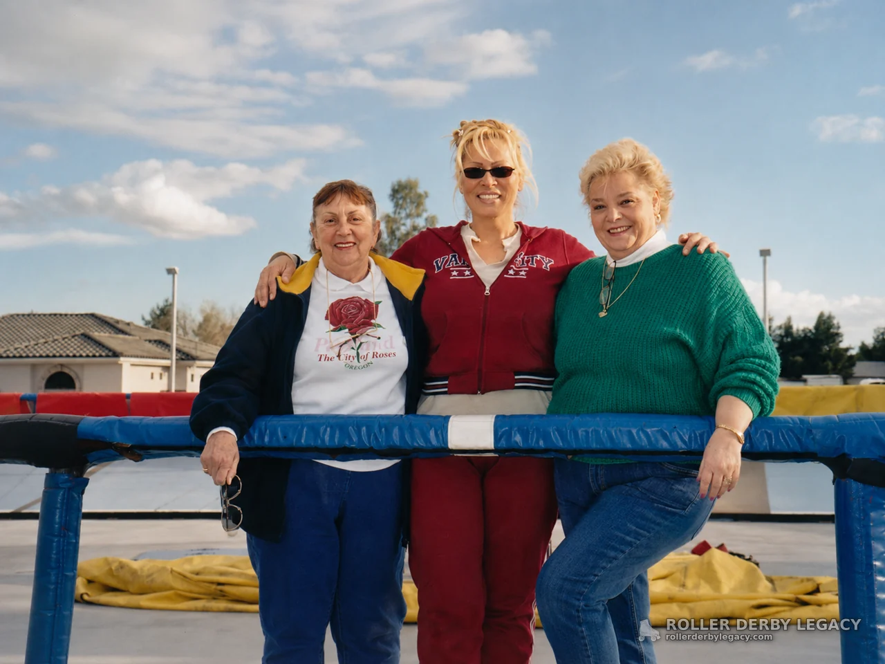 Three women posing behind padded outdoor ring ropes