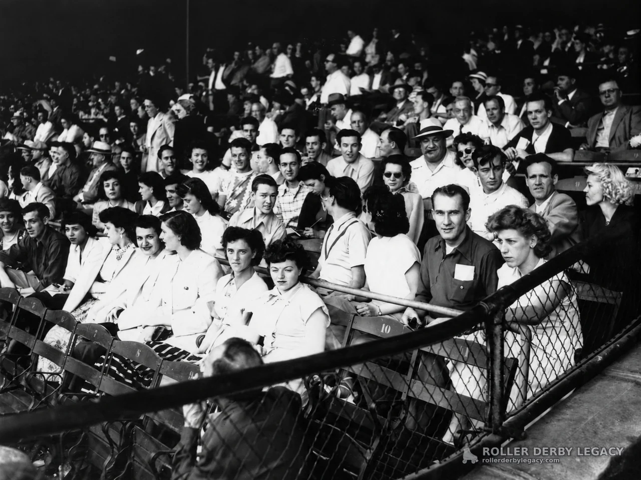 Spectators in Arena Seating Behind Chain-Link Railing