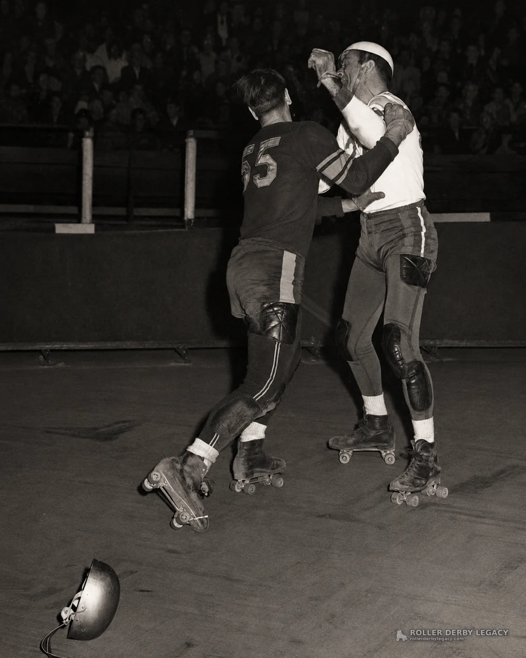 Roller Derby Skaters Grapple Near Rink Barrier