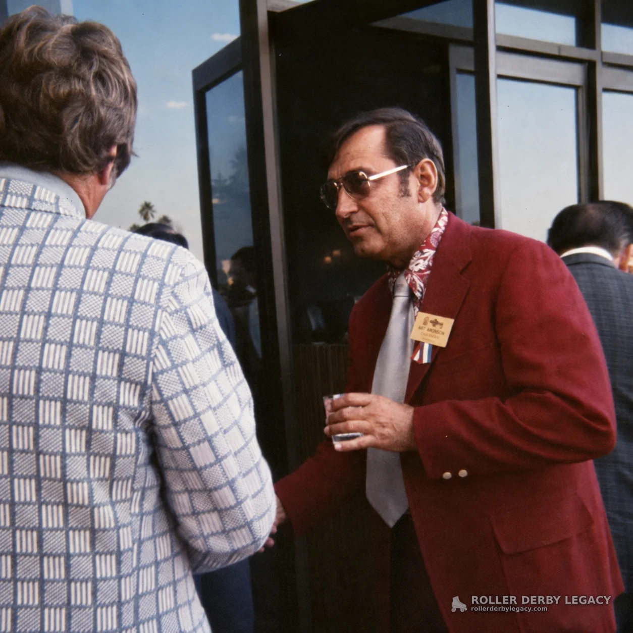 Man with Art Johnson Badge Outside Glass Entrance