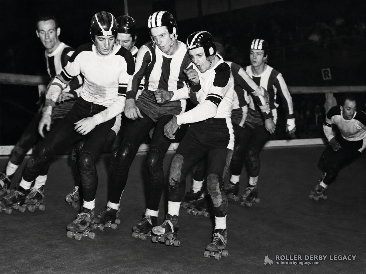 Helmeted Roller Derby Skaters Packed on an Indoor Track