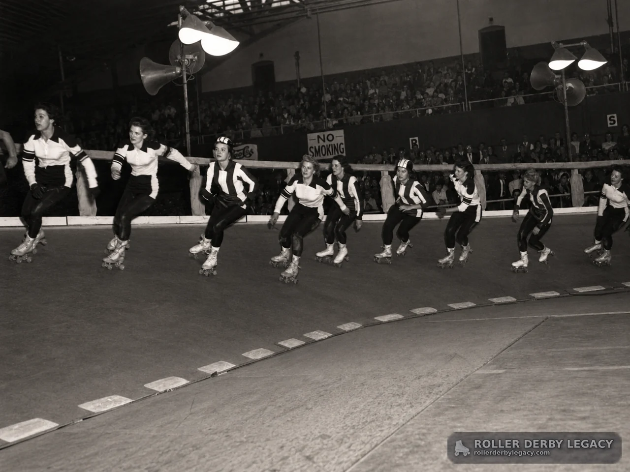 Roller Derby Skaters on an Indoor Track Before a Crowd