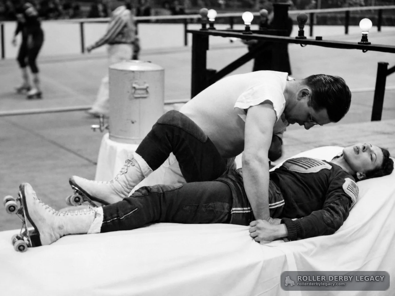 Skater Attended on Padded Table Beside Roller Derby Track