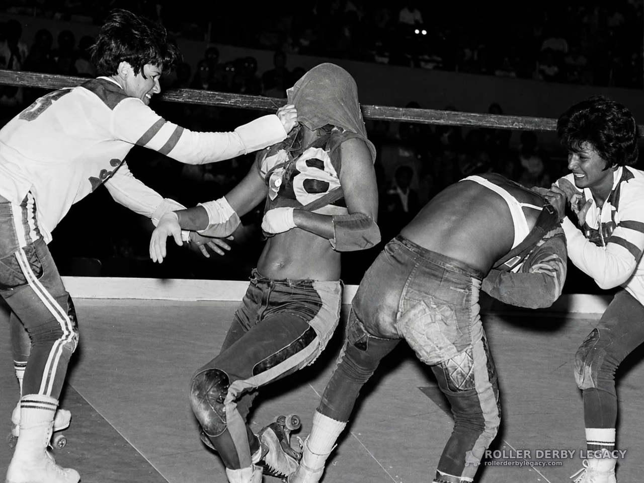 Roller Derby Skaters Grappling at the Track Barrier