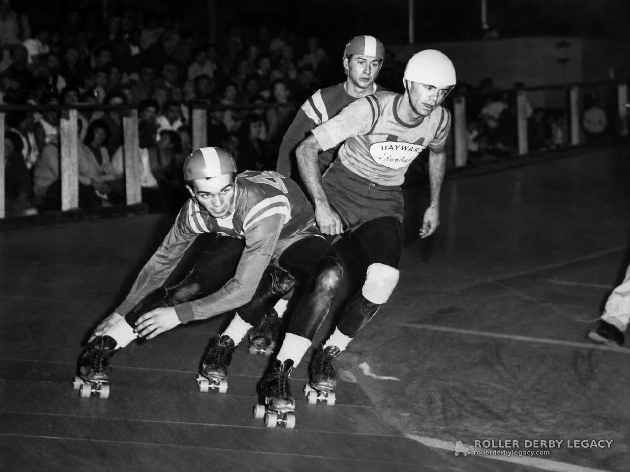 Three Roller Derby Skaters Racing Indoors