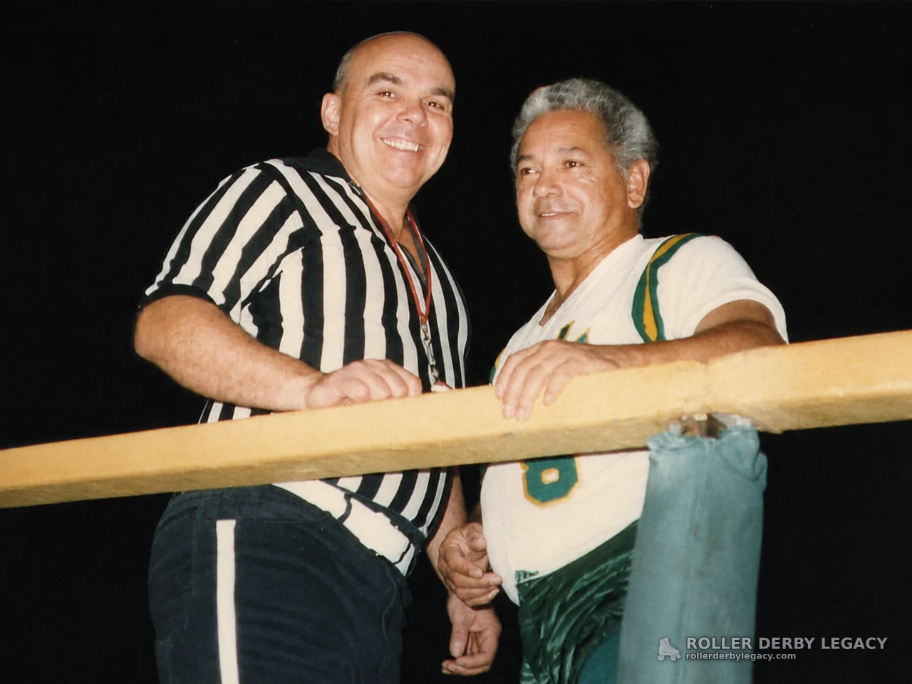 Two Roller Derby Men Behind a Padded Rail