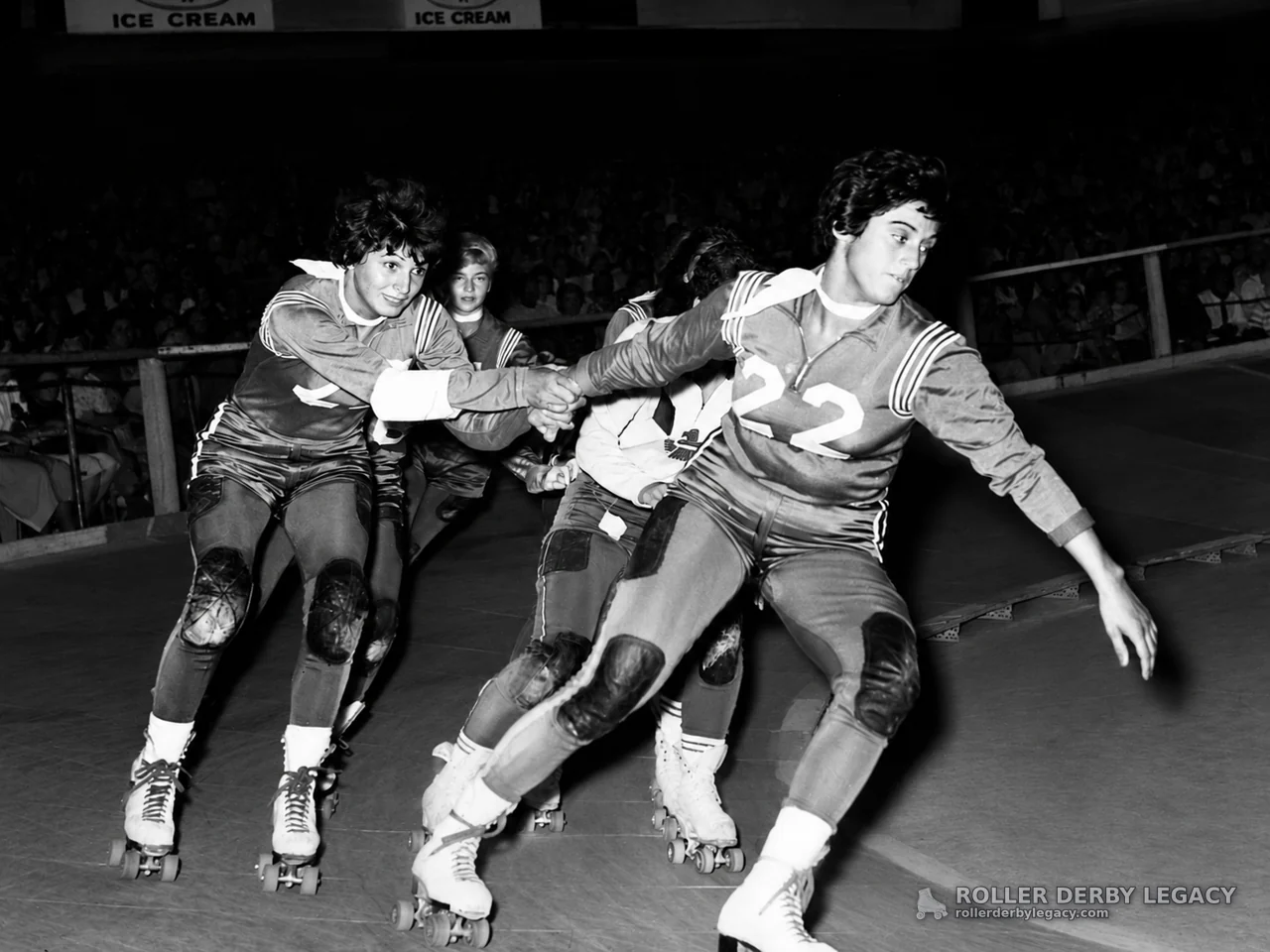 Roller Derby Skaters Holding Hands on Indoor Track