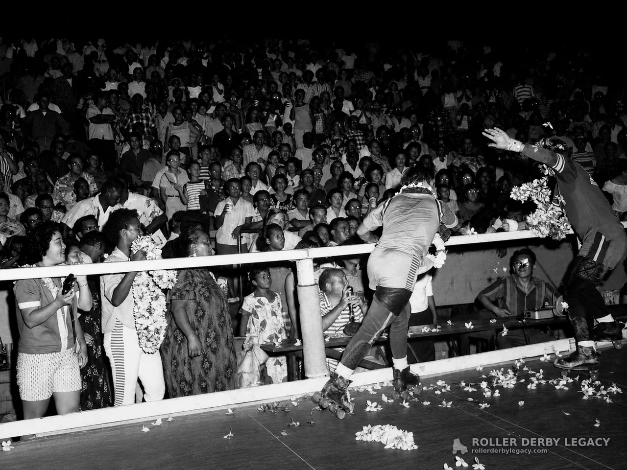 Roller skaters greet crowd amid flowers at rink barrier