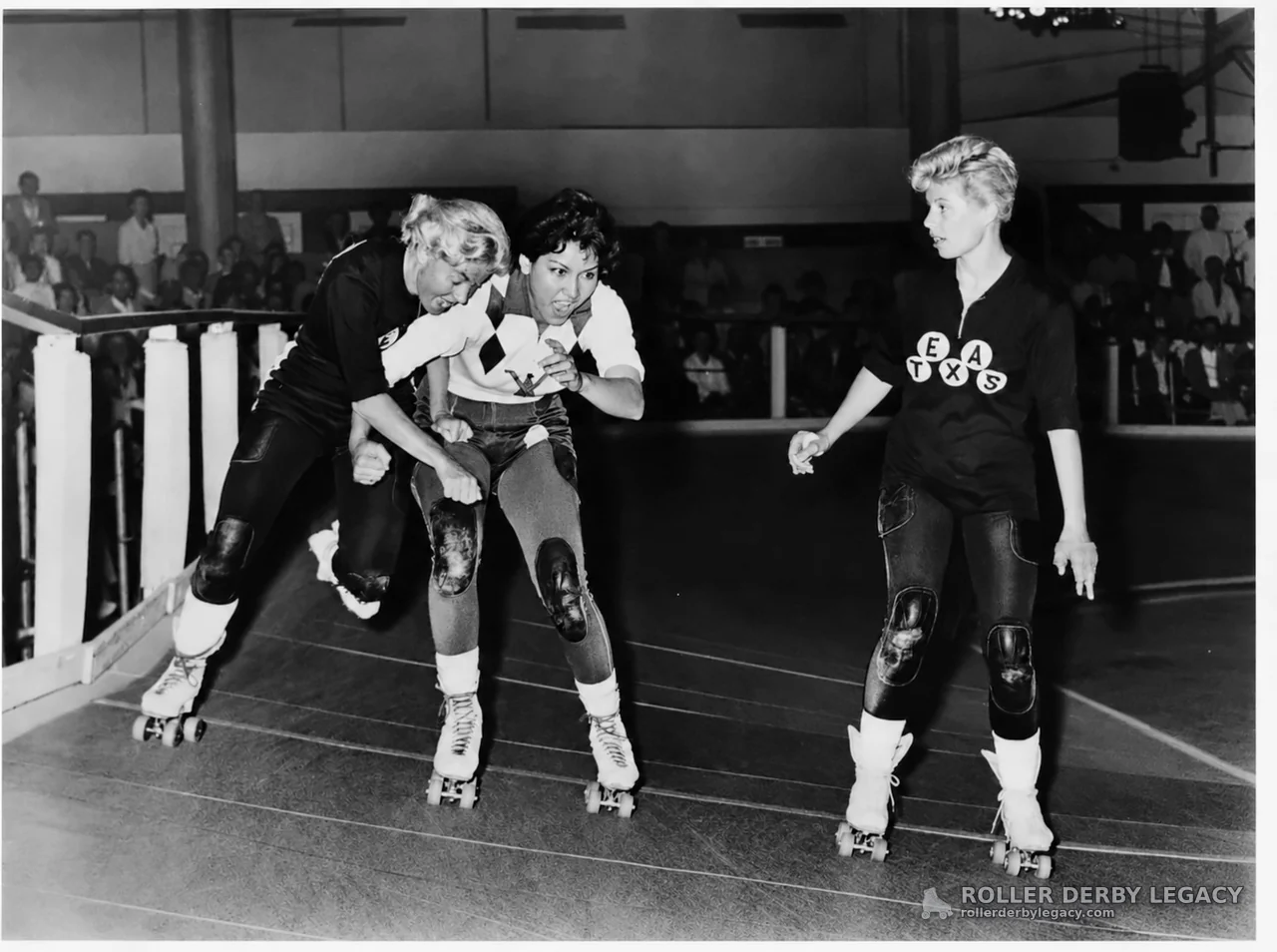 Three Roller Derby Skaters on an Indoor Track