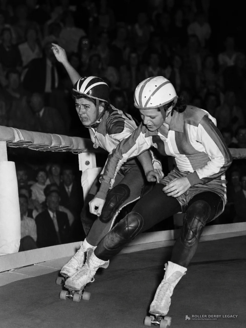 Two Roller Derby Skaters Lean Into a Track Turn