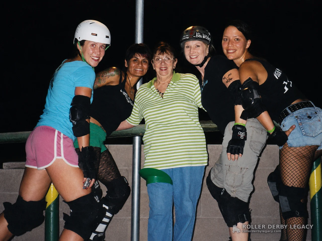 Five Women Posing in Roller Derby Gear by a Railing
