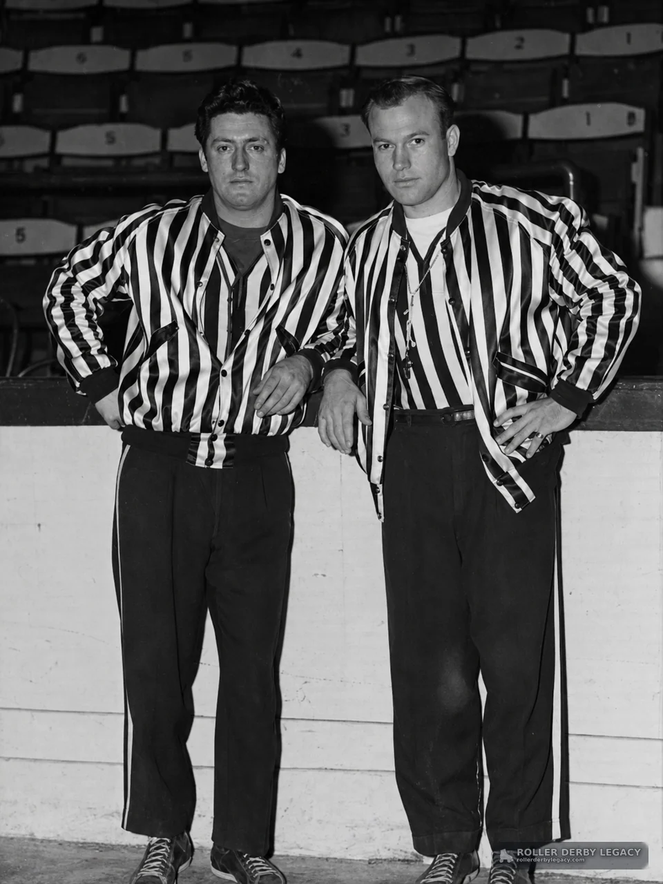 Two Roller Derby Officials at a Rink Barrier