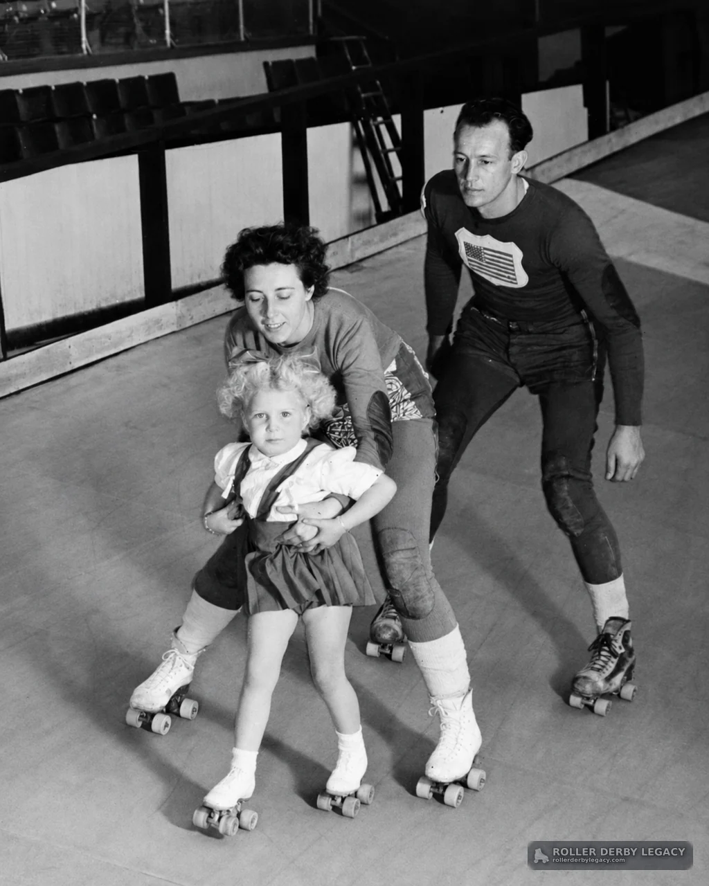Adults Helping a Child Skate on an Indoor Rink