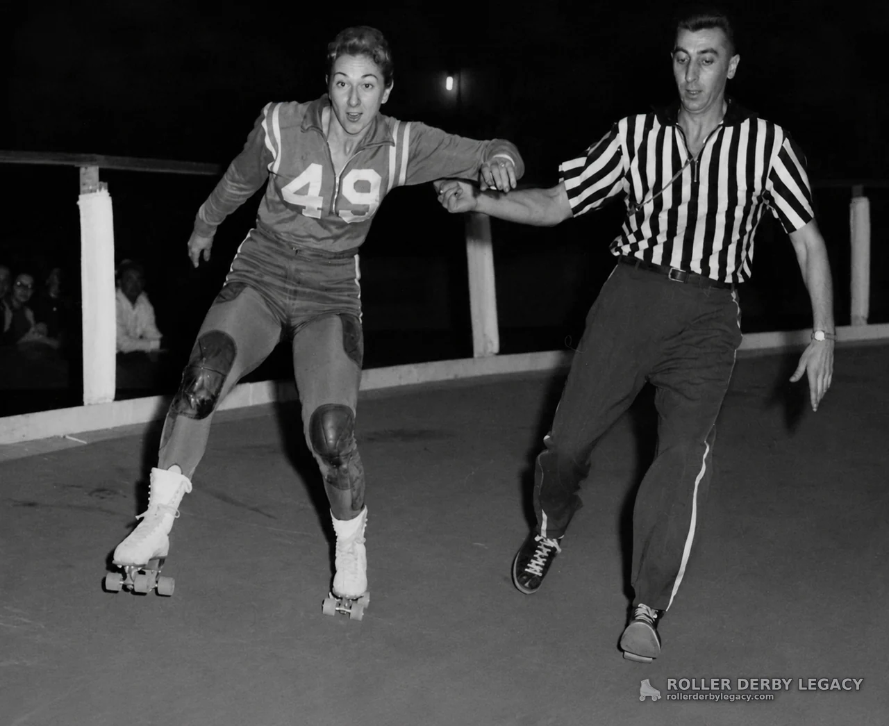 Skater 49 with Striped-Shirt Official on Rink