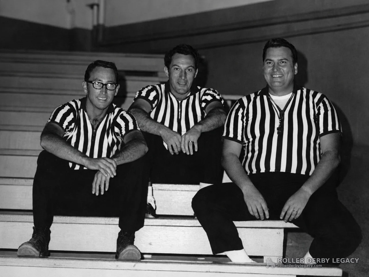 Three Referees Seated on Indoor Bleachers