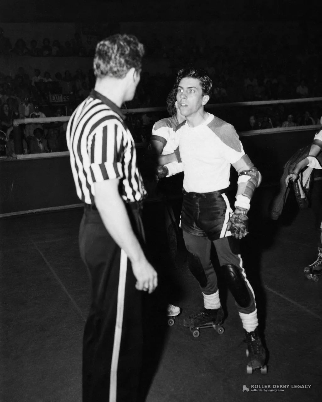 Referee Facing Roller Derby Skaters on Indoor Track