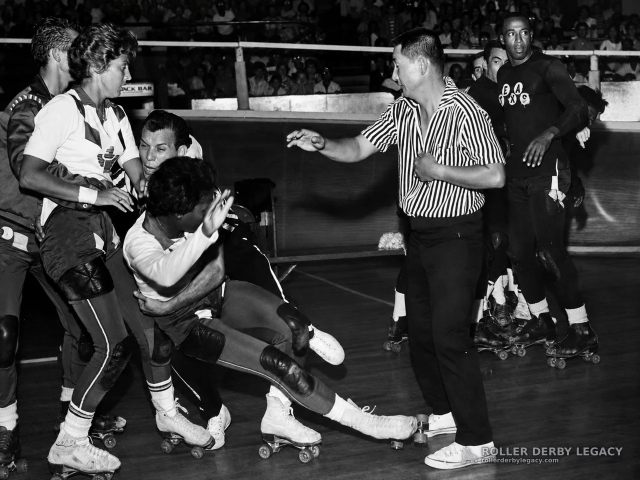 Roller Derby Pileup with Referee at Indoor Rink