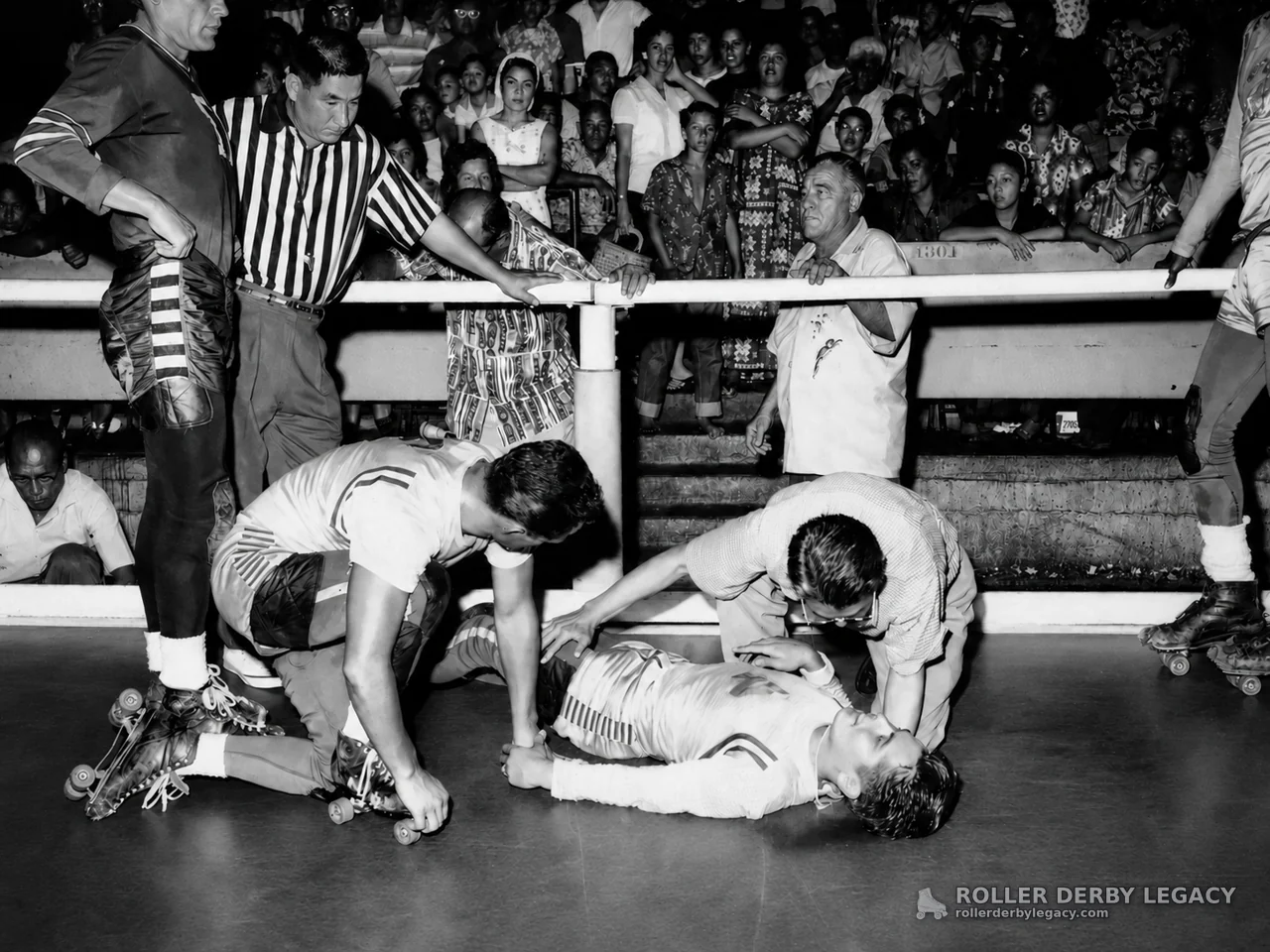 Fallen roller derby skater attended beside rink rail