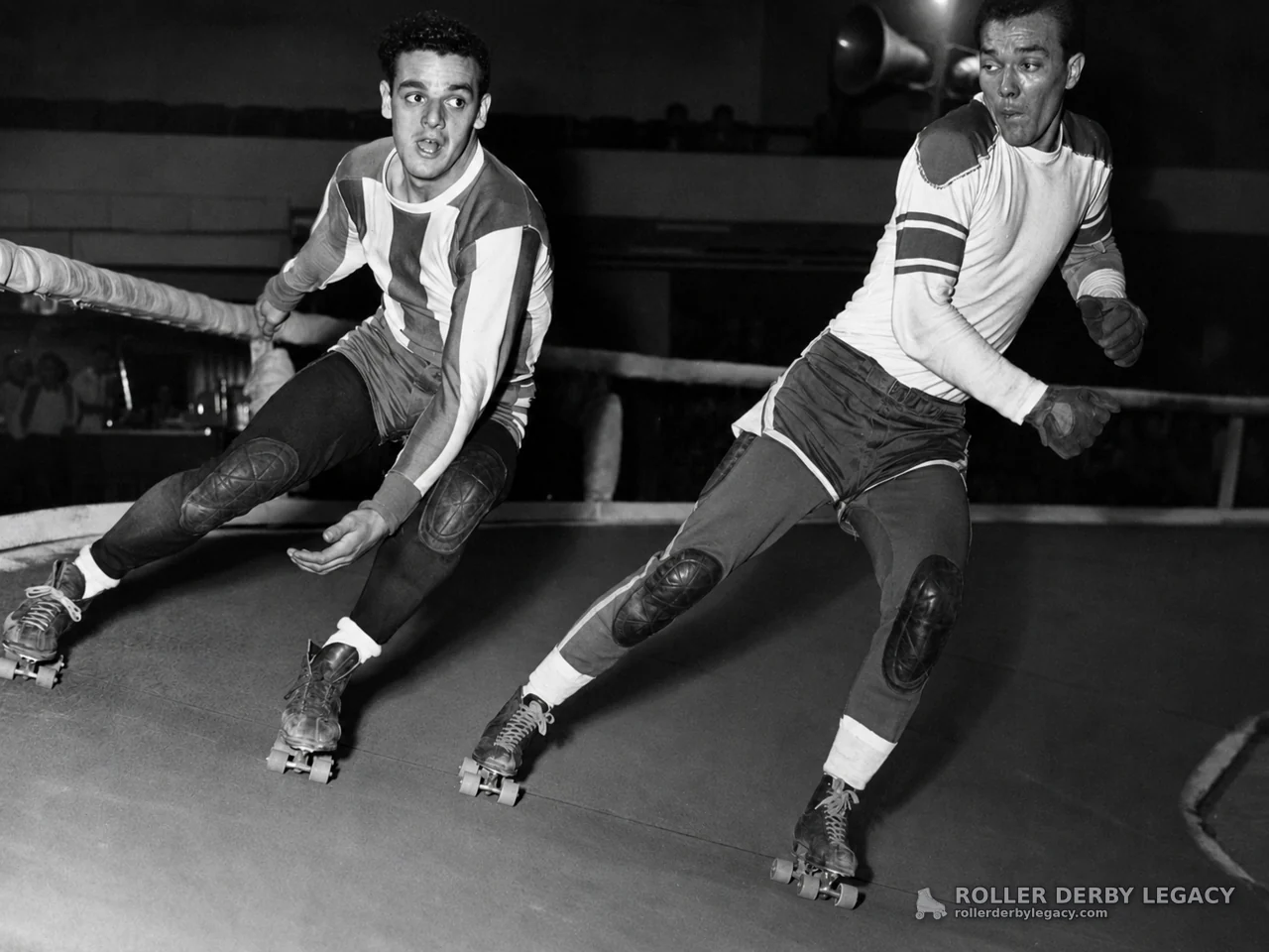 Two Roller Derby Skaters Leaning Through an Indoor Turn