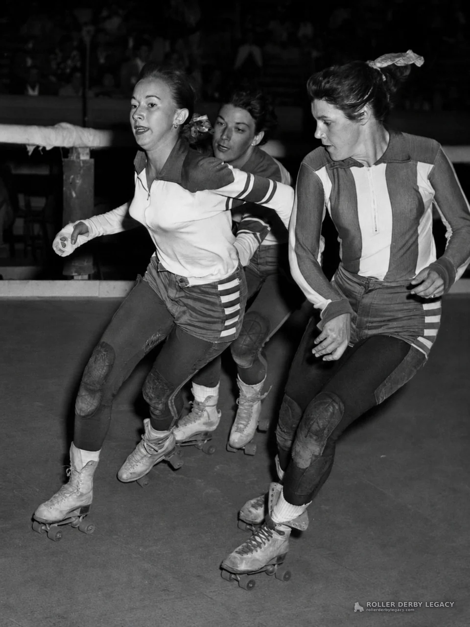 Three Roller Derby Skaters on an Indoor Track