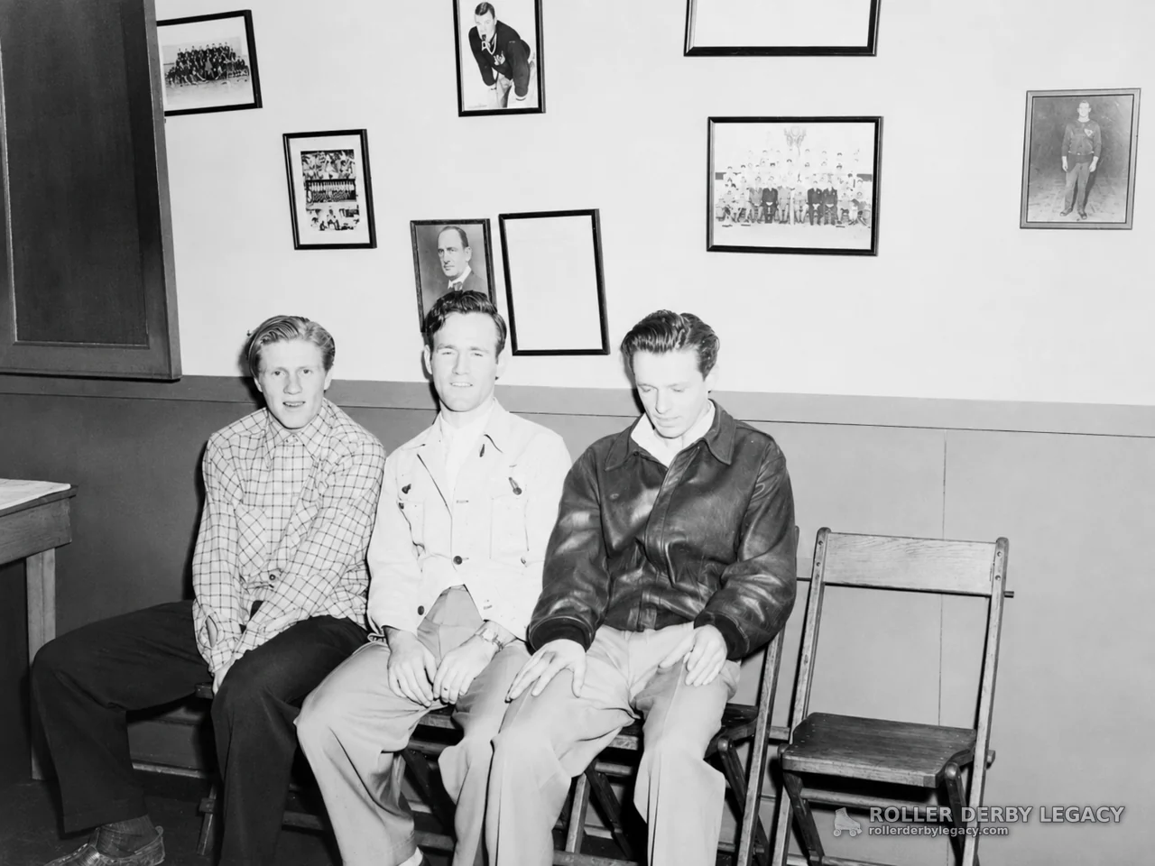 Three Men Seated Beneath Framed Photographs