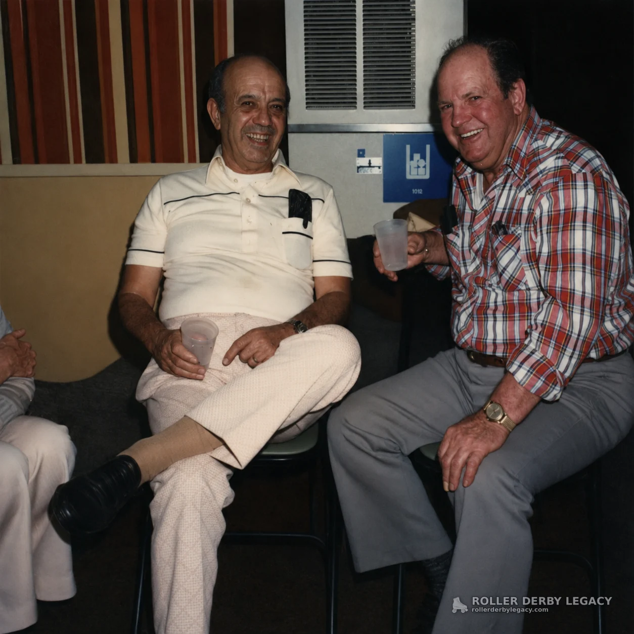 Two Men Seated with Cups in an Indoor Seating Area