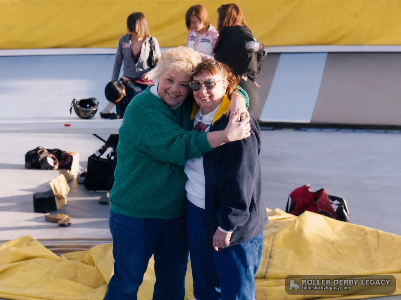 Two Women Embracing Near Yellow Barrier
