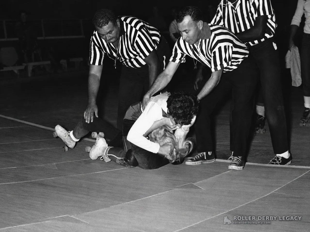 Referees Attend to Tangled Skaters on the Rink Floor